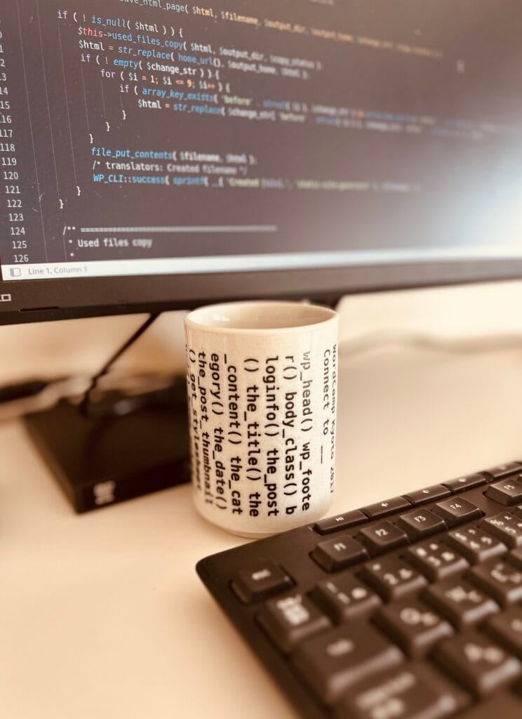 WordPress code displayed on a monitor beside a keyboard and teacup